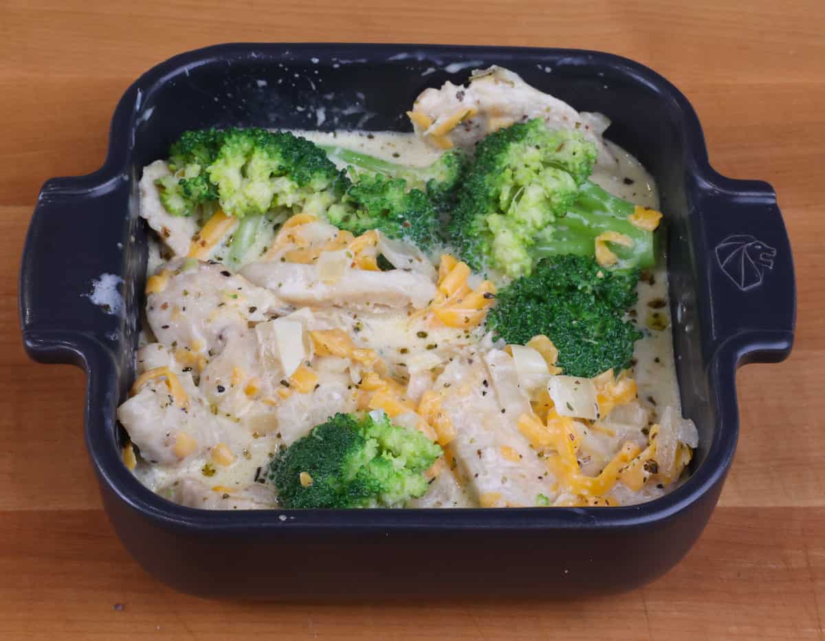 uncooked chicken divan in a small black square baking dish