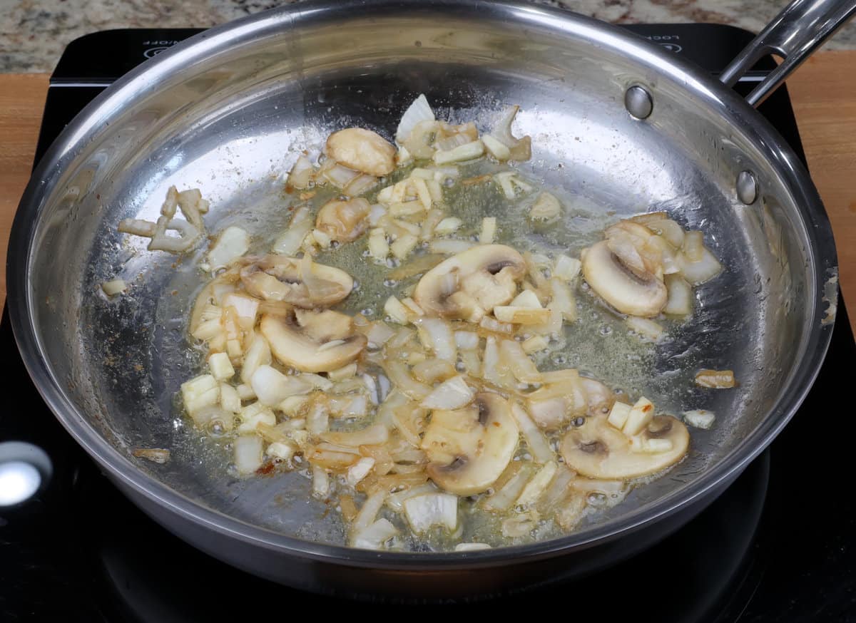 chicken, onions, and garlic cooking in a skillet