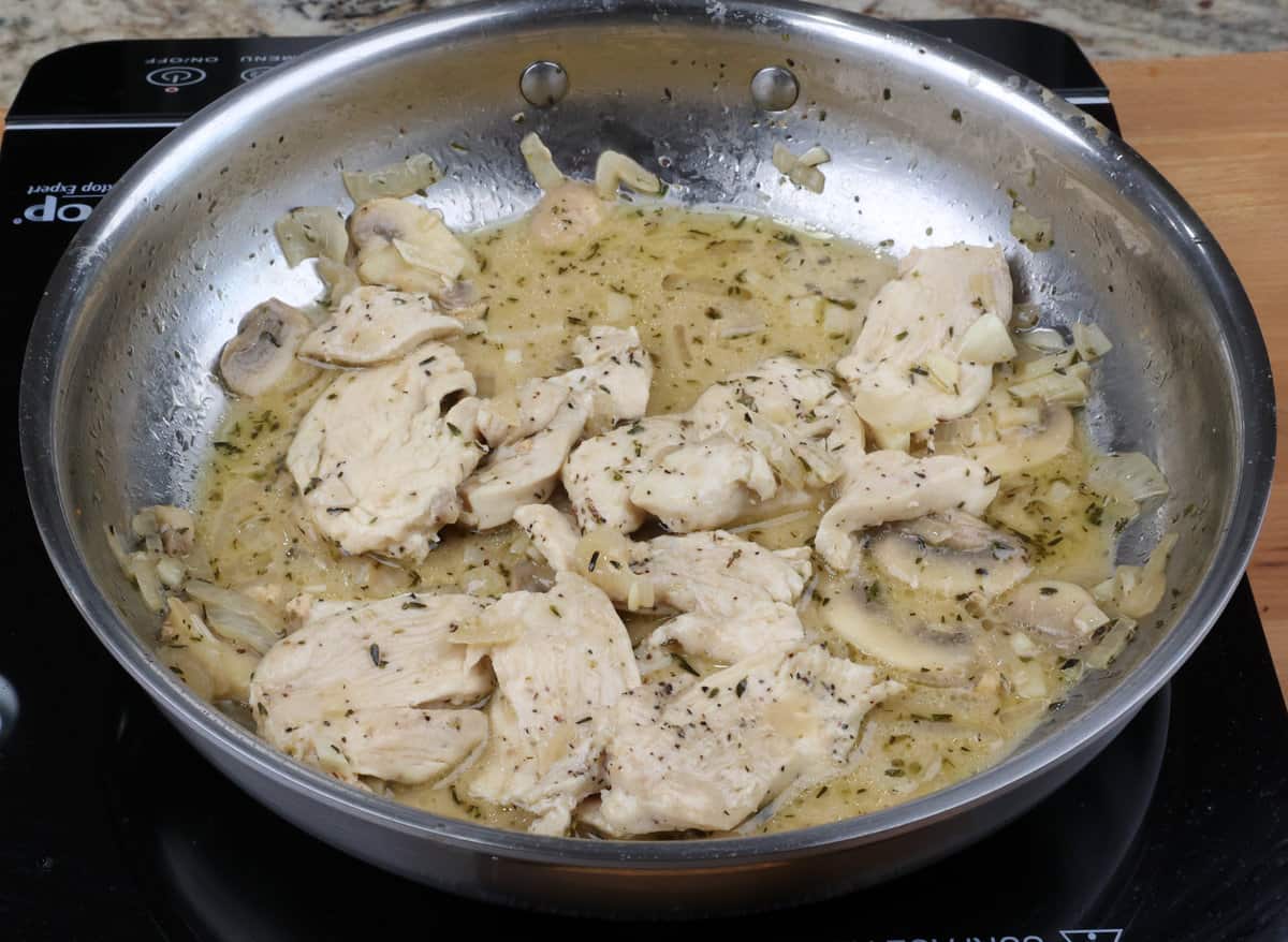 chicken marsala with mushrooms simmering in a pan on the stove.
