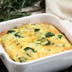 a small coronation quiche baked in a white square baking dish next to fresh tarragon