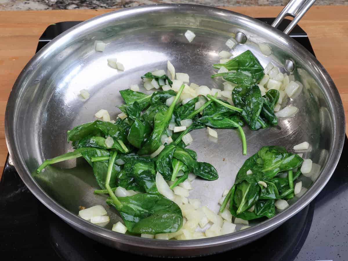 wilted spinach, onions and garlic in a skillet