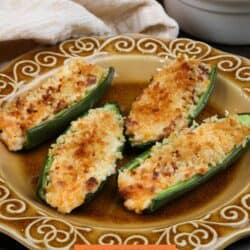 four cheese stuffed jalapeno poppers on a gold plate.