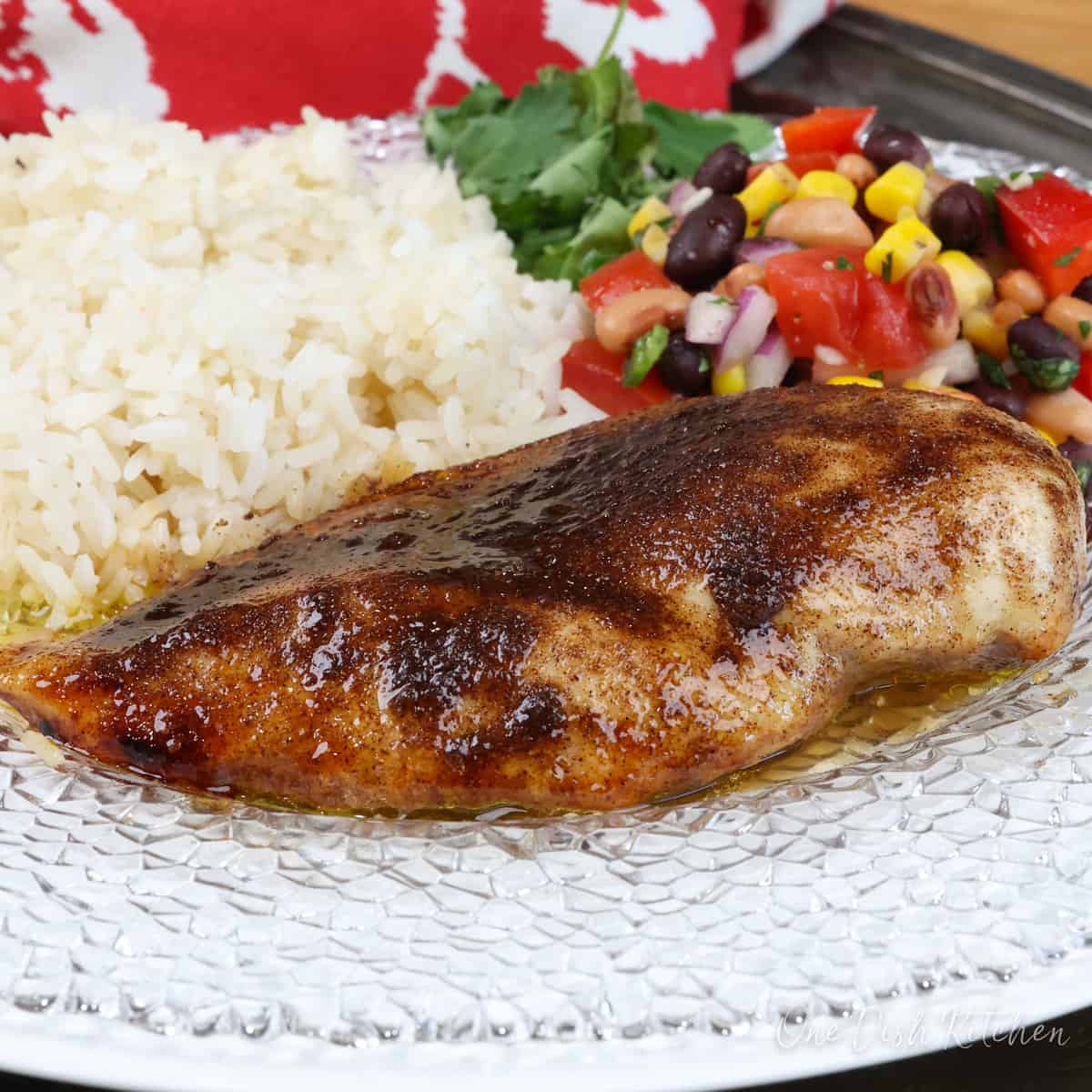 a chicken breast coated with jerk seasoning on a white plate next to a red napkin