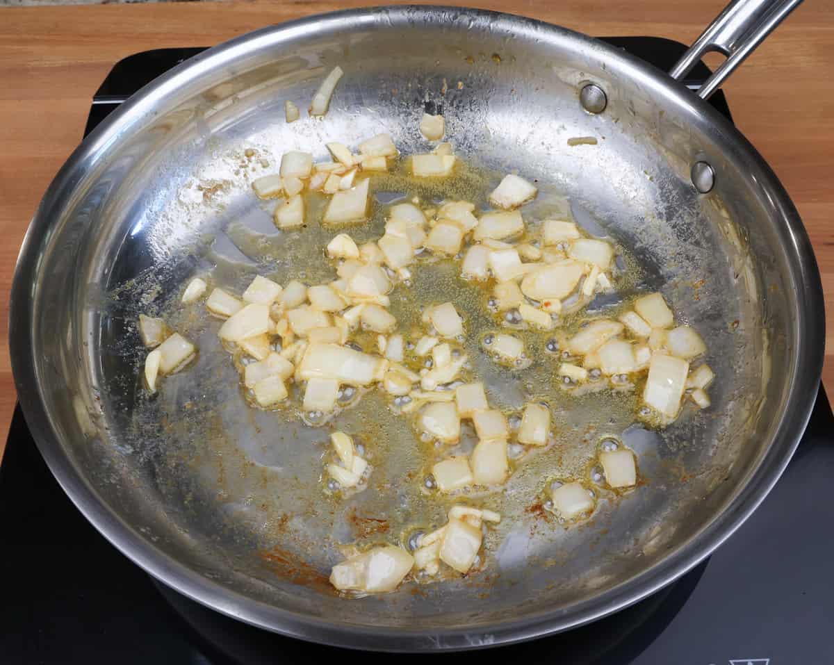 onions and garlic cooking in a skillet.