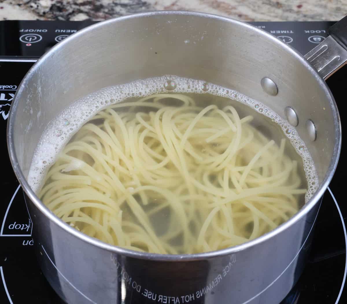 pasta cooking in a small pot on the stove.