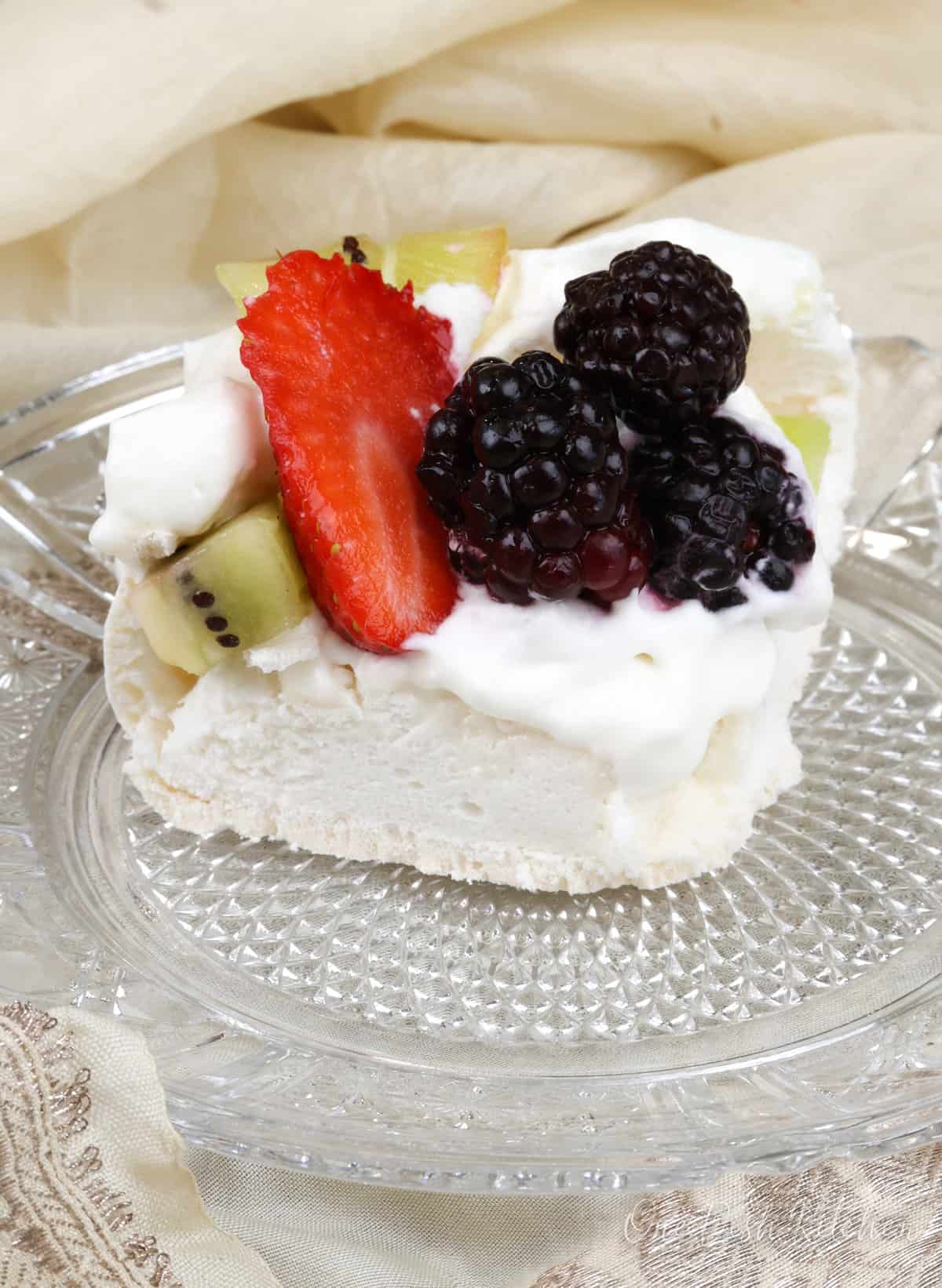 a piece of pavlova on a white plate topped with fruit