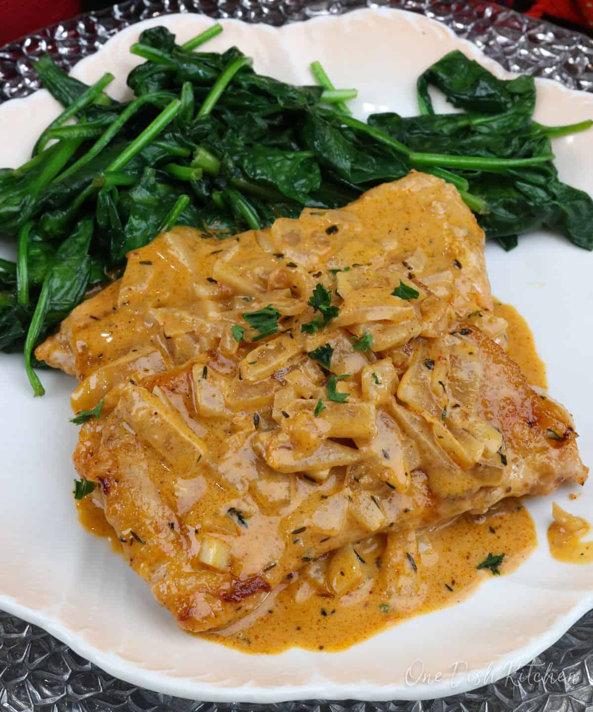 two boneless pork chops topped with onion gravy on a plate.