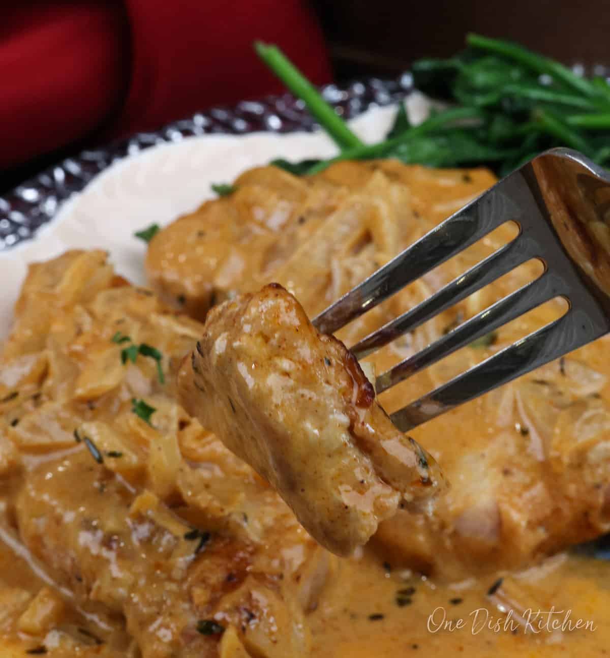 a pork chop with gravy on a fork.