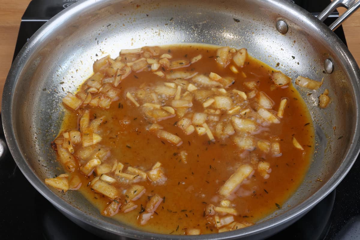 chicken broth, onions and garlic cooking in a skillet on the stove