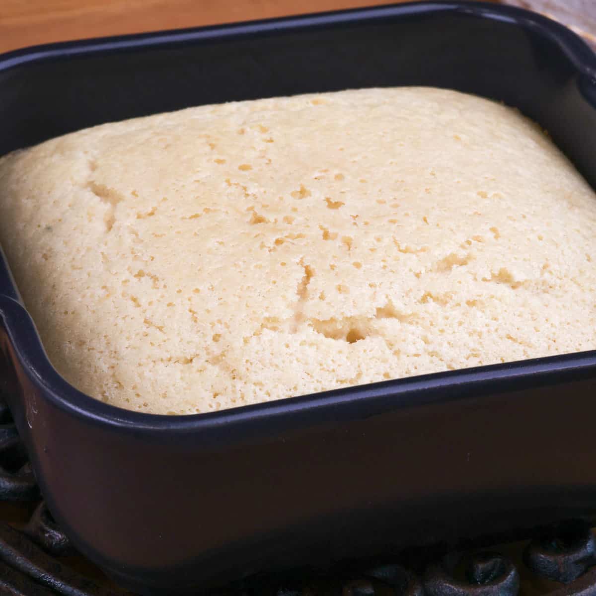a white cake in a small black baking dish