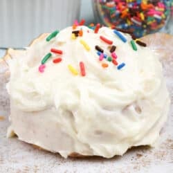 a small white cake on a white plate topped with colored sprinkles next to a ramekin