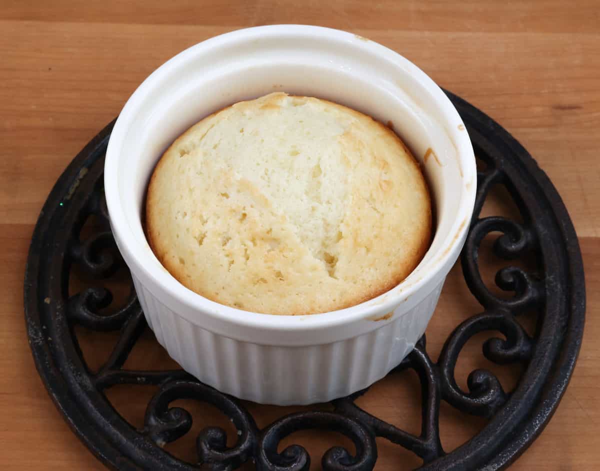 a small white cake on a cooling rack on a kitchen counter.