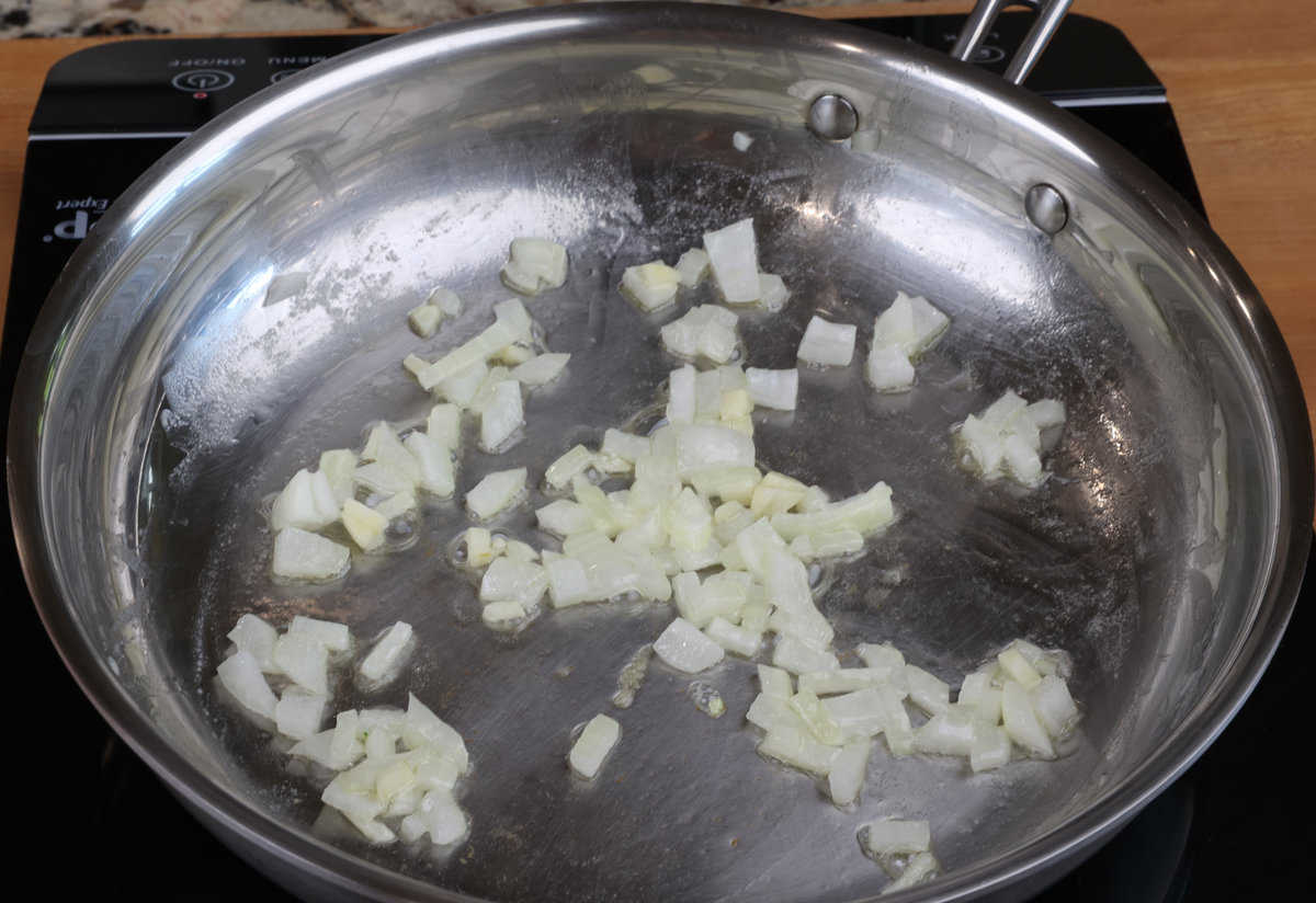 chopped onions and garlic in a skillet on the stove.