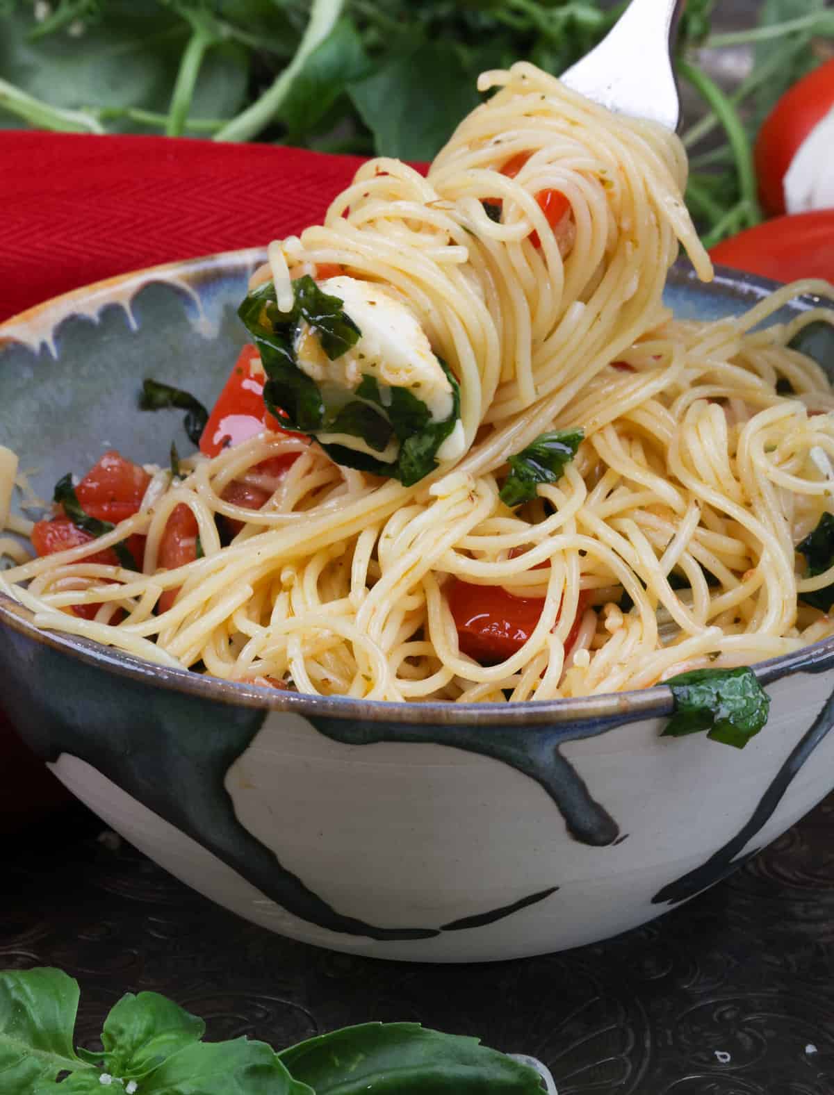 a fork filled with caprese pasta over the bowl.