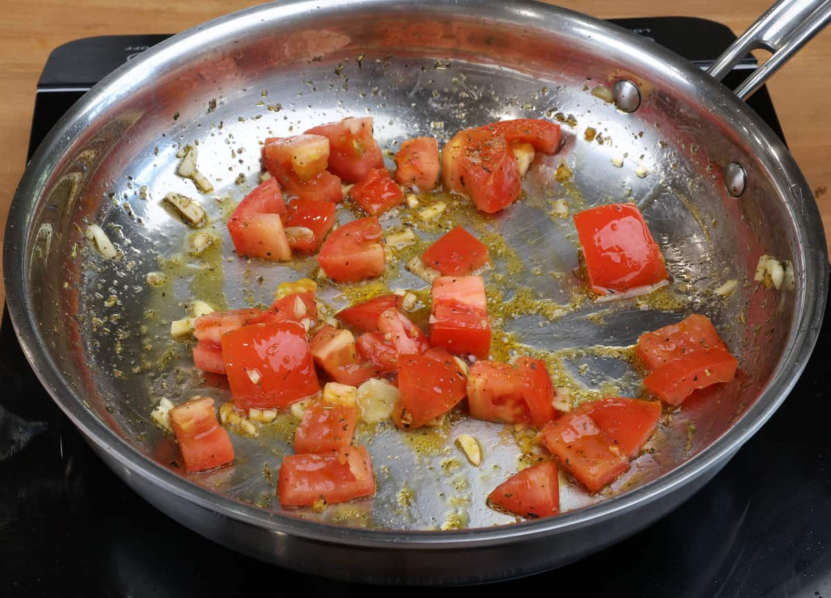 chopped tomatoes and garlic sauteeing in a skillet with olive oil.