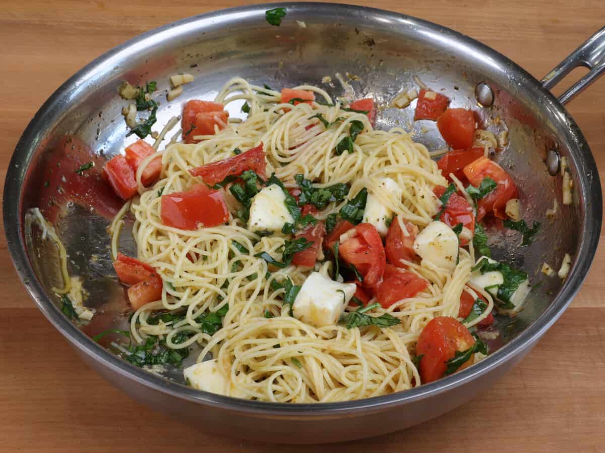 spaghetti tossed with fresh basil, cubes of mozzarella cheese and chopped tomatoes in a skillet.