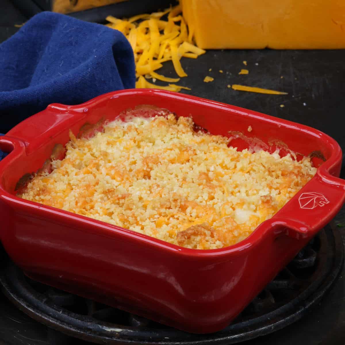 funeral potatoes in a small red baking dish next to a blue napkin.