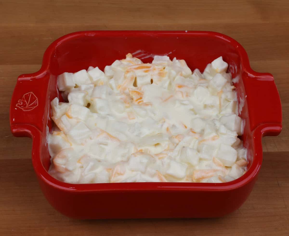 cheesy potatoes in a small red baking dish.