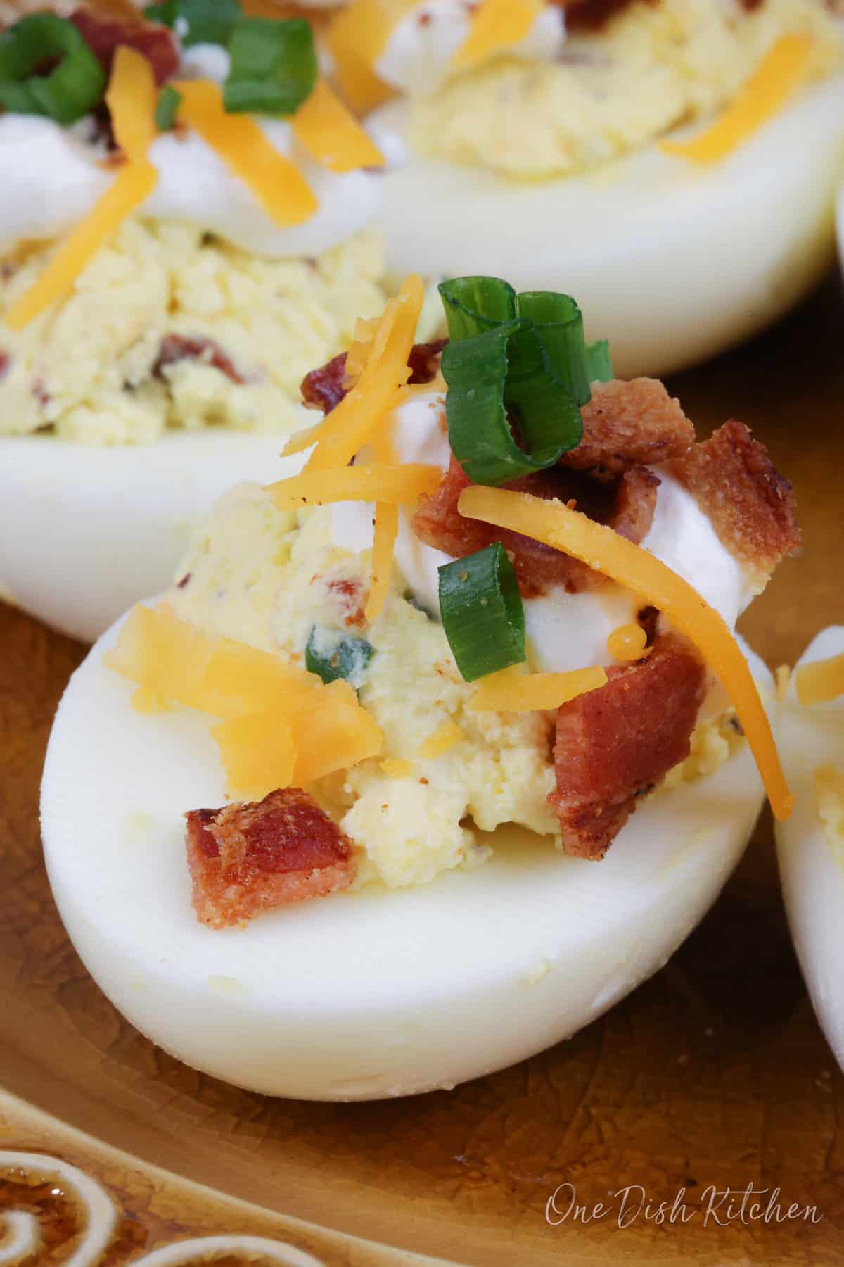 one loaded deviled egg with bacon on a gold plate