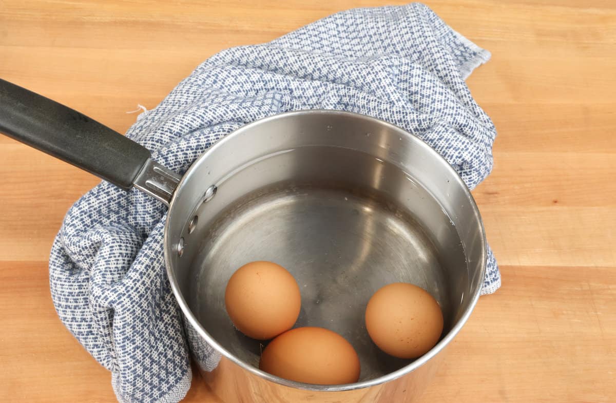 three eggs boiling in a pot.