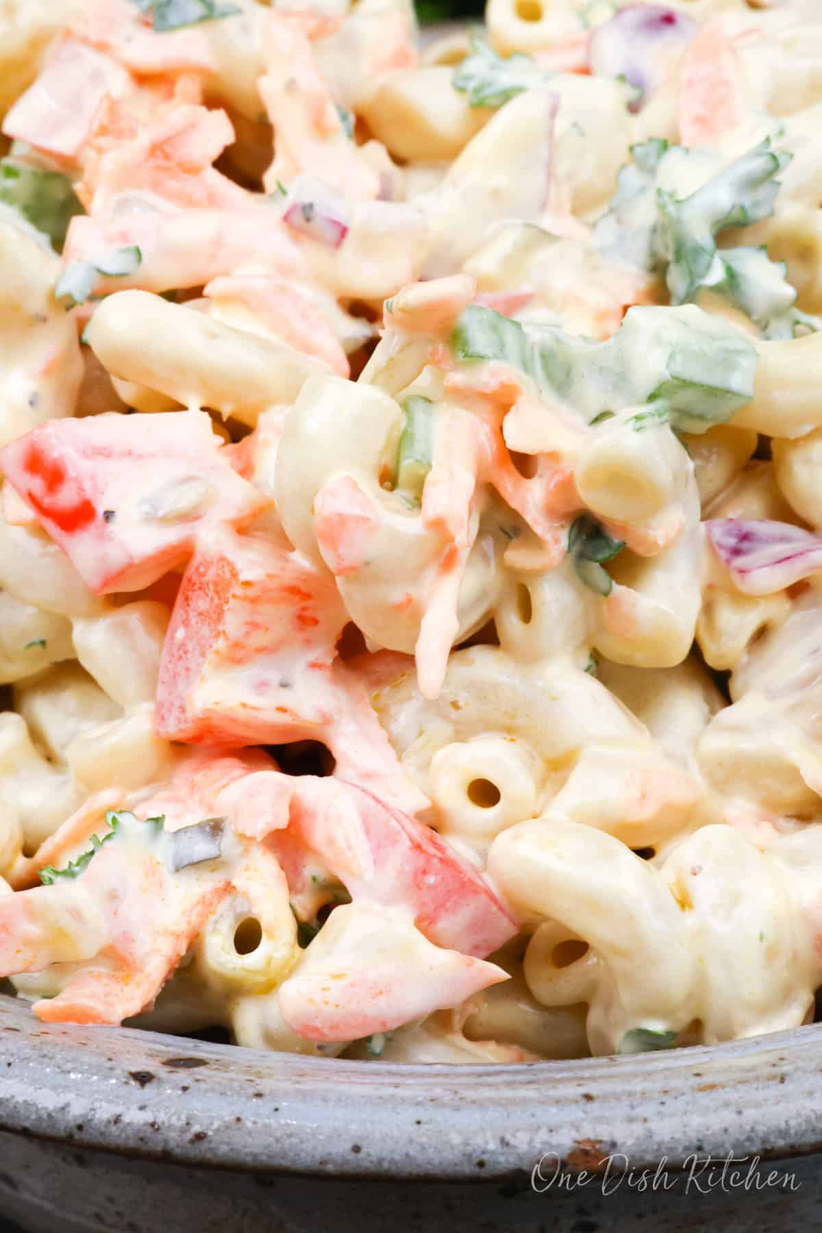 a close up photo of a macaroni salad with chopped vegetables and a creamy dressing.