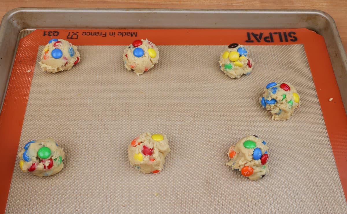 M&M cookie dough balls on a baking sheet.