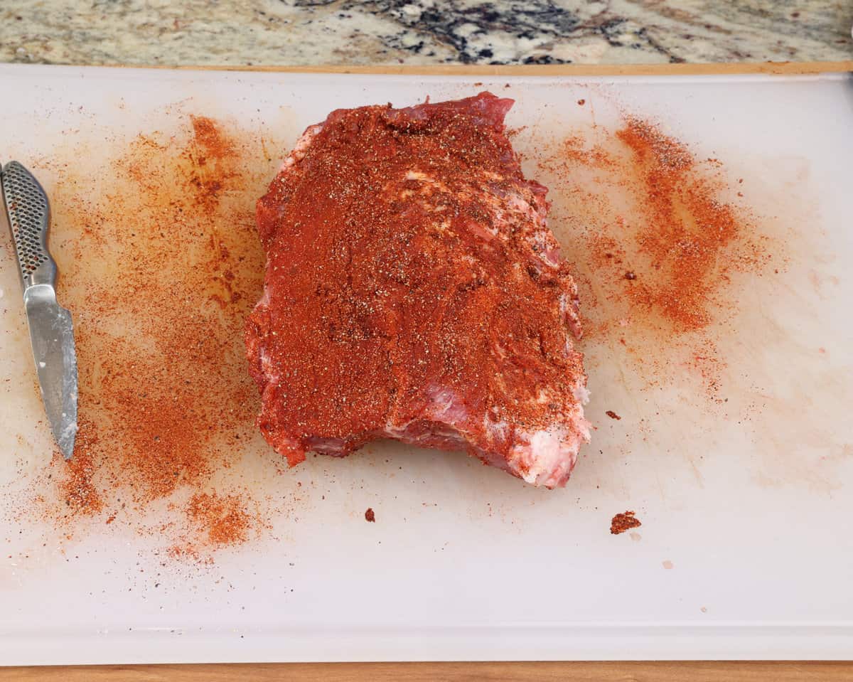 baby back ribs with dry rub on a white cutting board