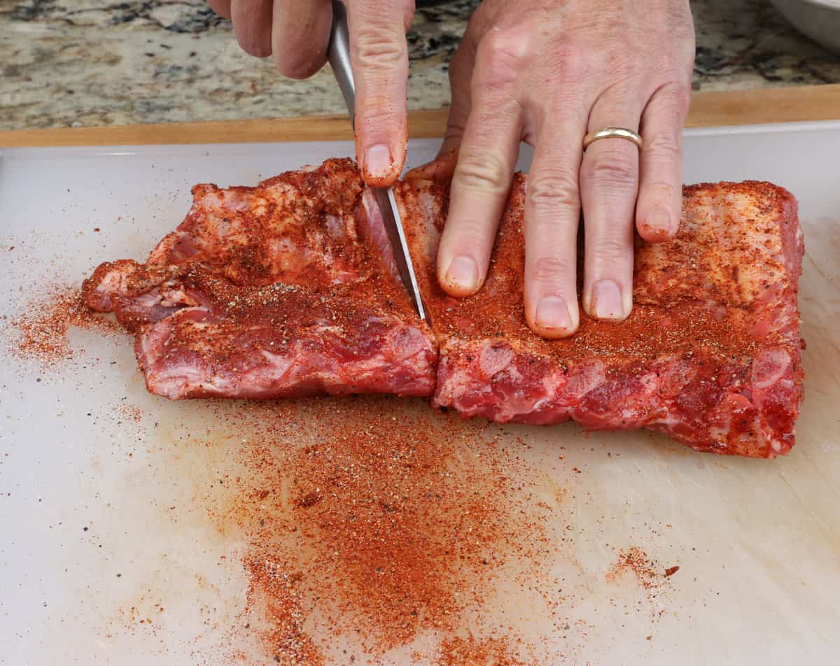 cutting a rack of ribs in half on a cutting board.