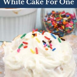 a small white cake topped with frosting and candied sprinkles on a plate,