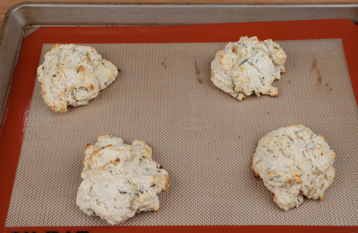 four baked garlic rosemary biscuits on baking sheet.