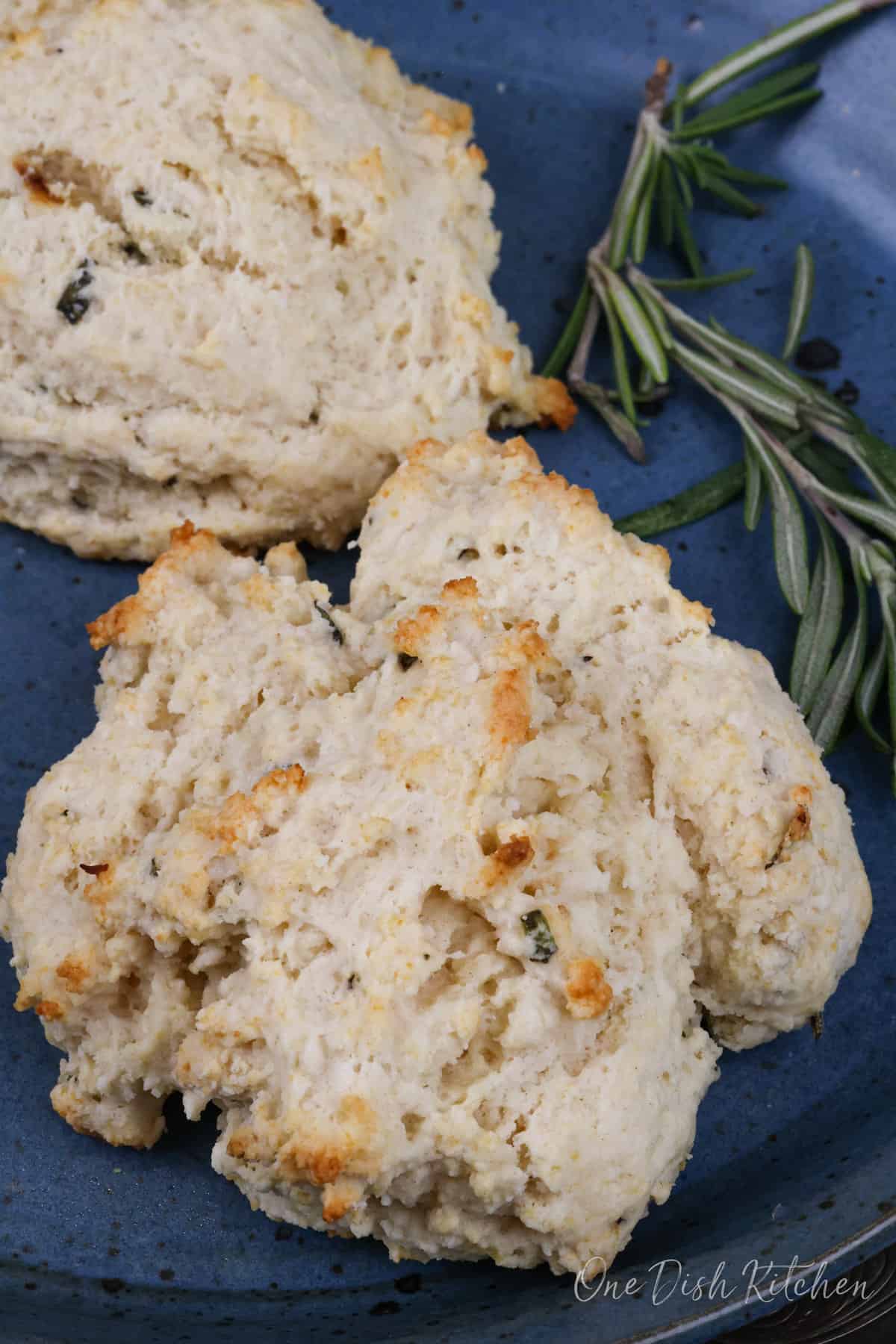 two rosemary garlic buttermilk biscuits on a blue plate.
