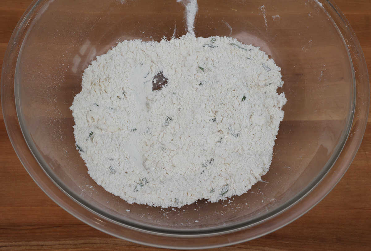 chopped rosemary whisked into flour in a mixing bowl.
