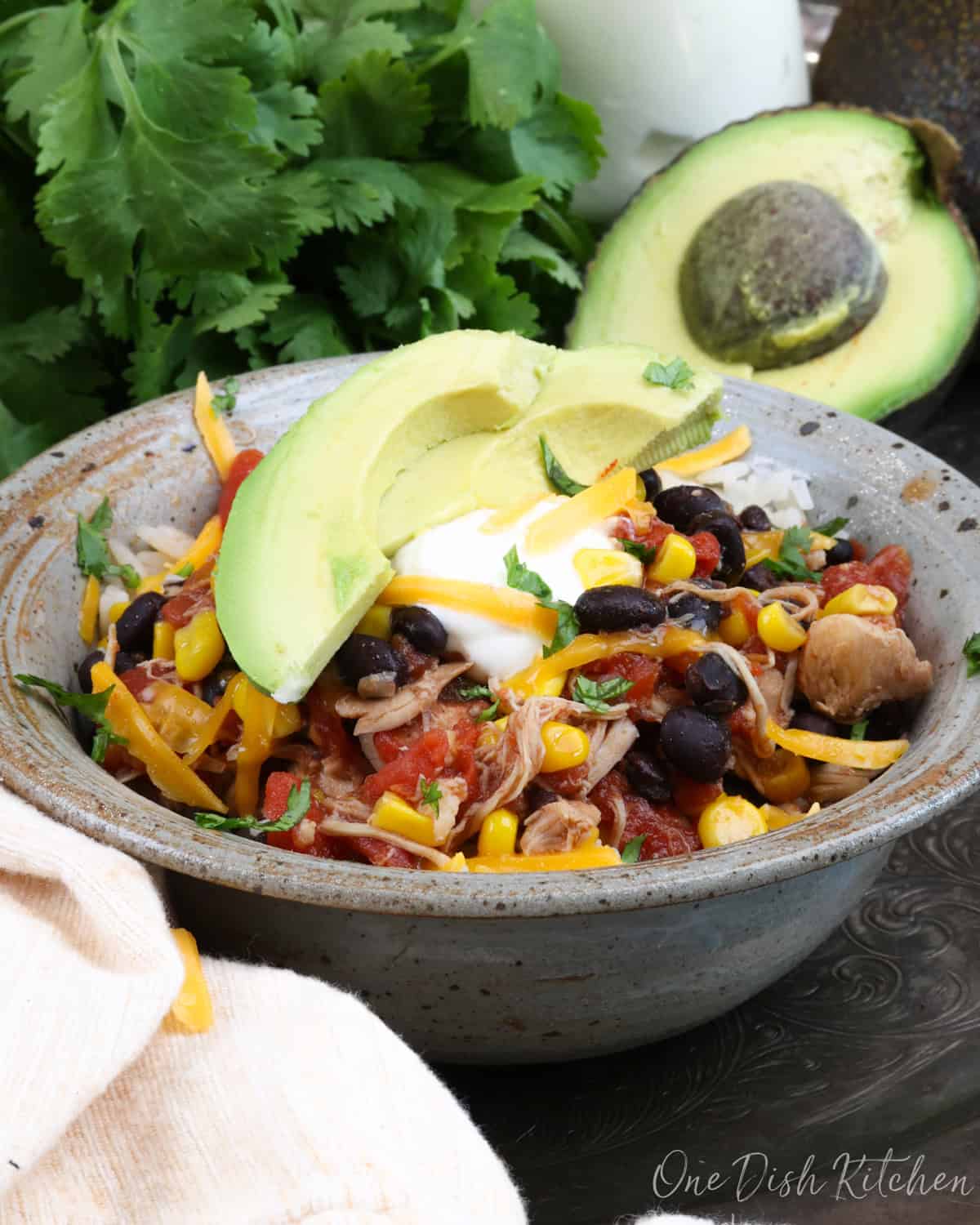 chicken burrito bowl on a silver tray next to fresh cilantro and an avocado.