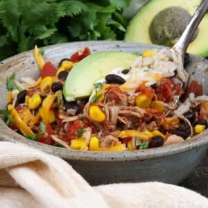 a deconstructed burrito in a bowl with a fork on the side.