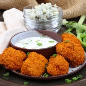 5 buffalo cauliflower nuggets on a plate next to a bowl of blue cheese dressing