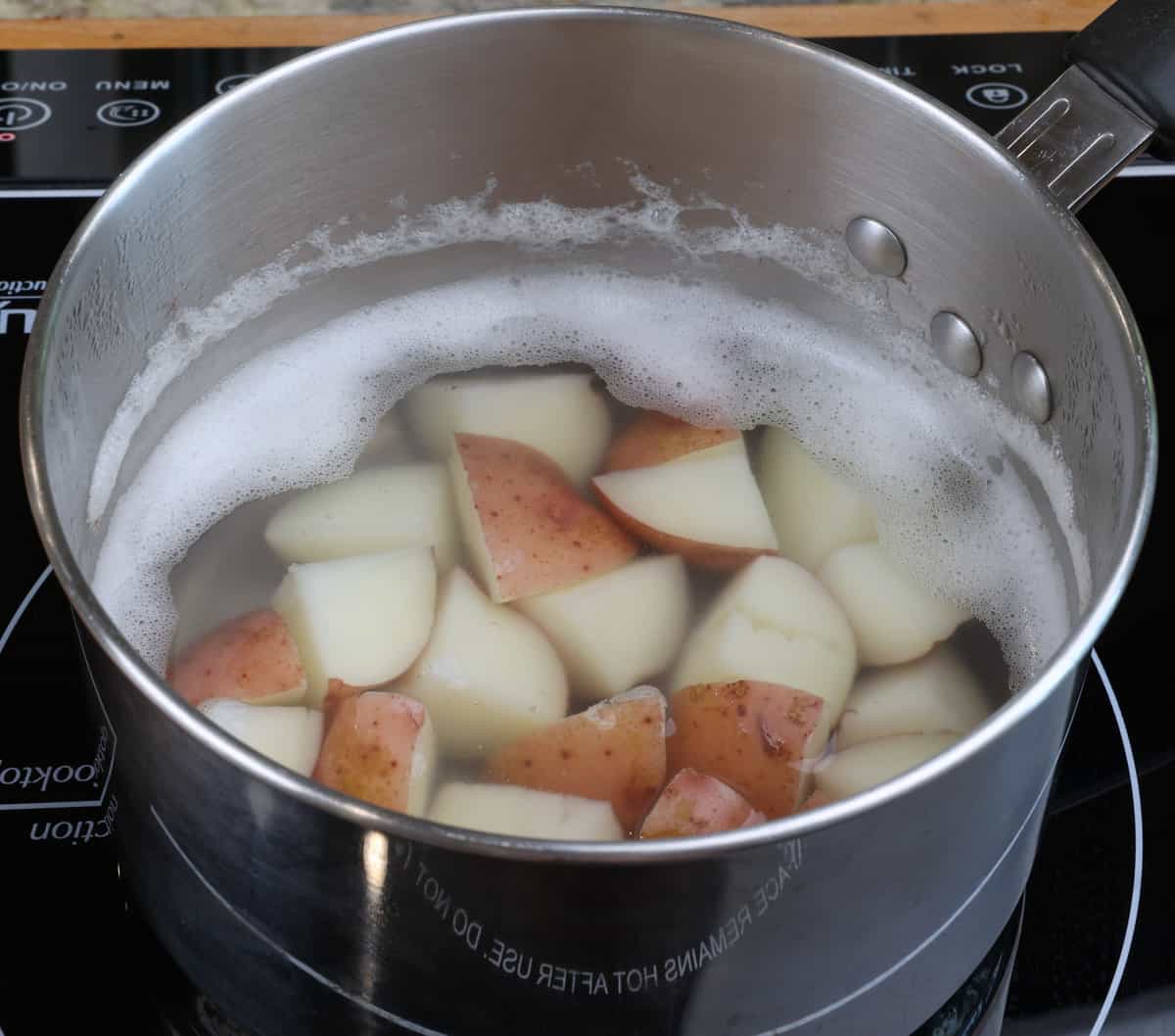 potatoes cooking in a pot of water on the stove.