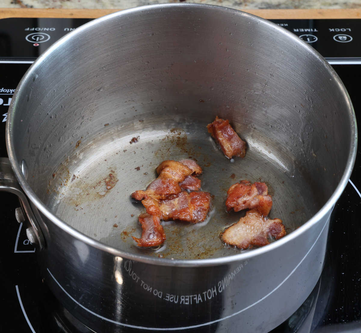 bacon pieces cooking in a small pot.
