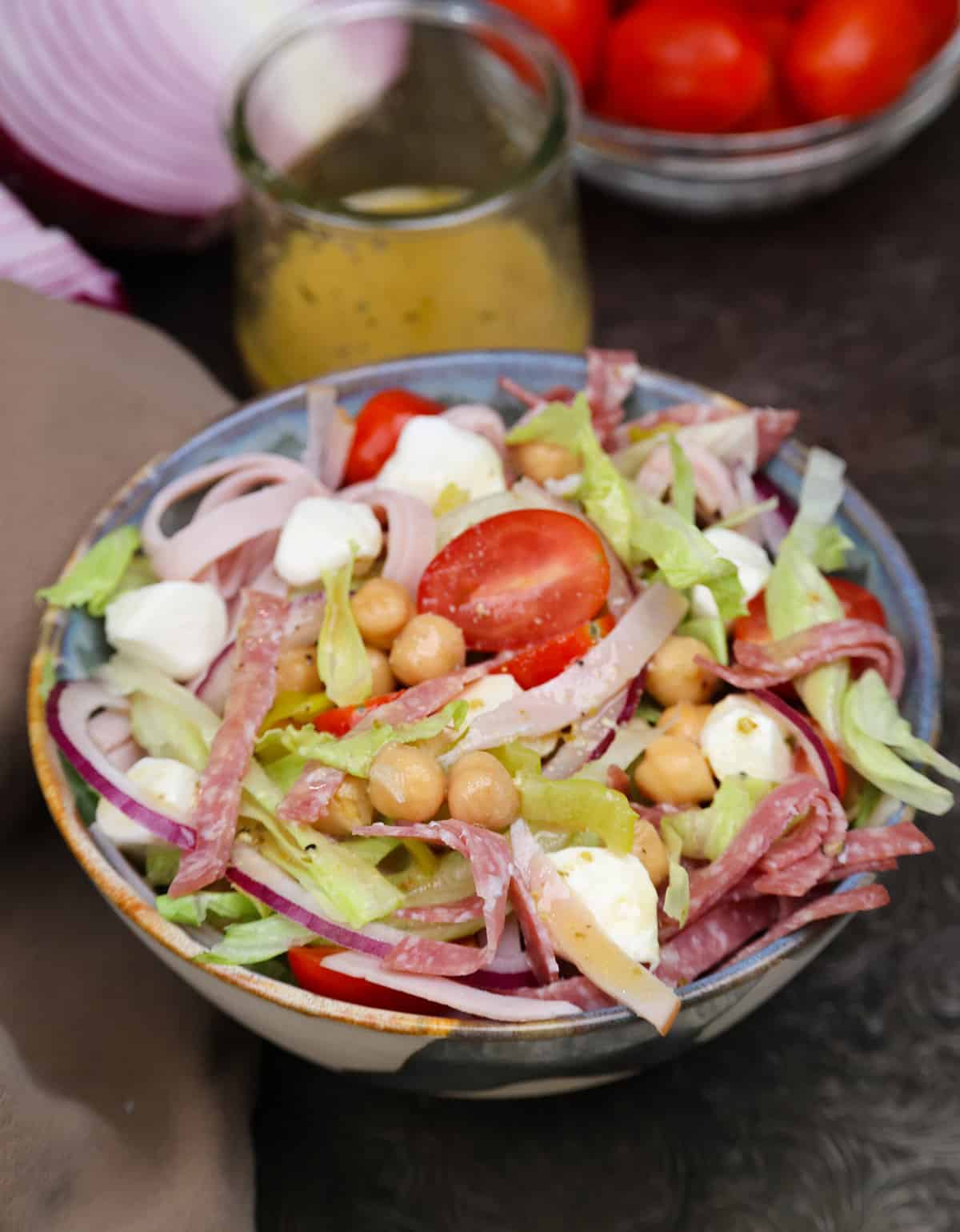 an italian chopped salad in a bowl next to a jar of vinaigrette.