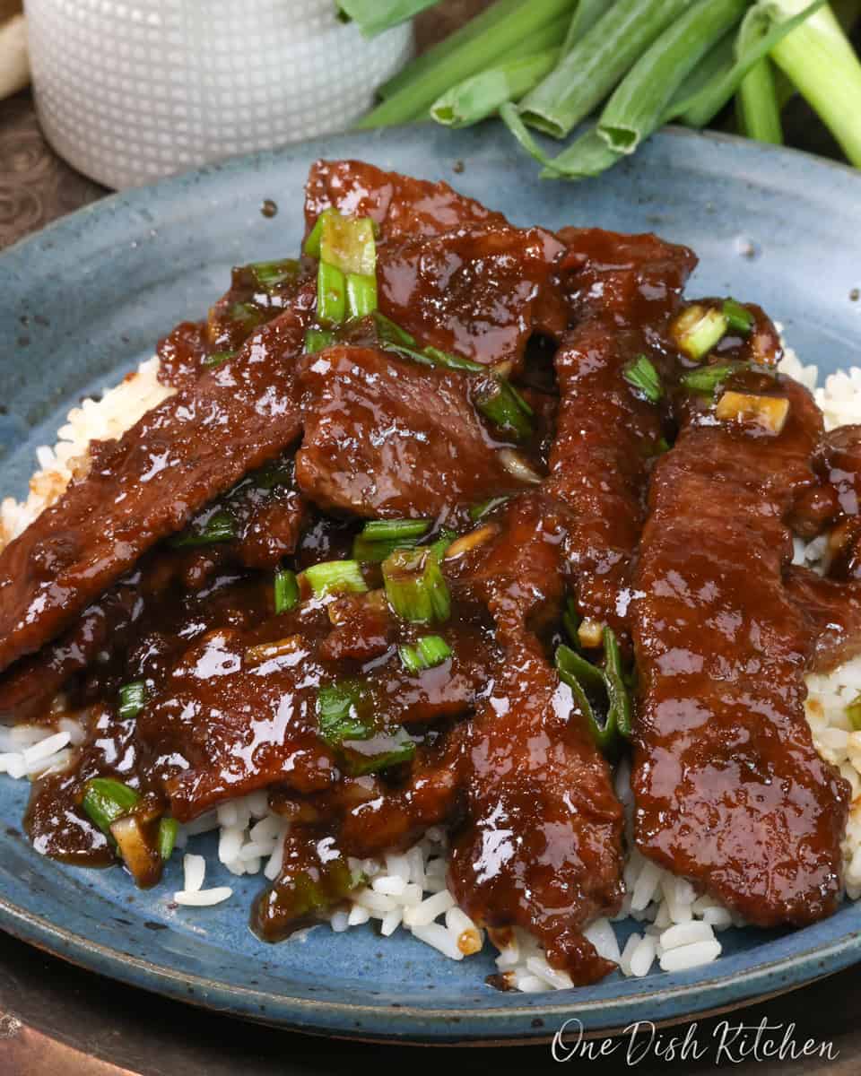 Mongolian Beef over rice on a blue plate.