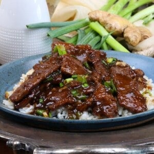 mongolian beef served over white rice on a silver tray