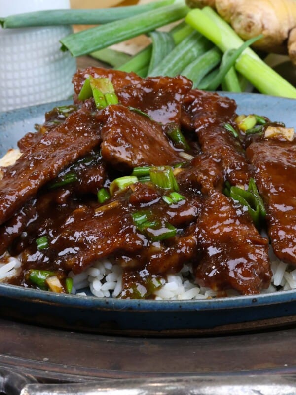 mongolian beef served over white rice on a silver tray.