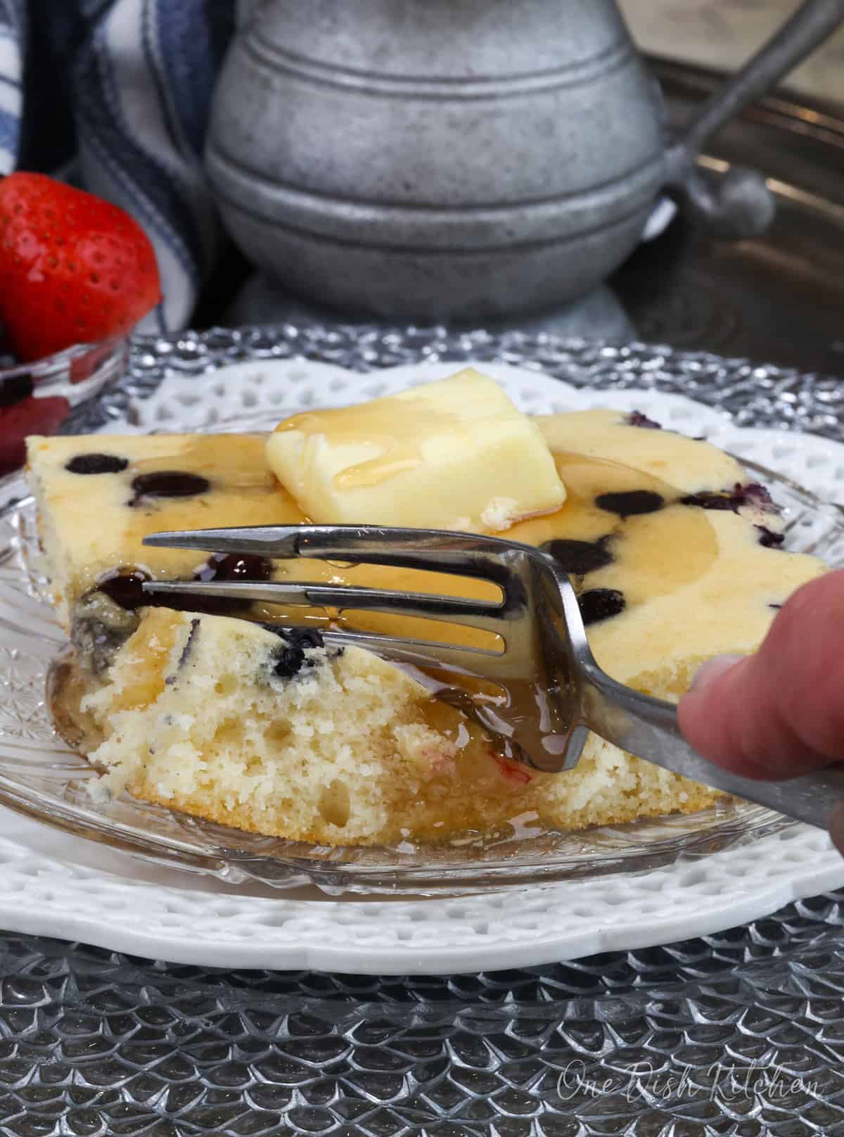 a fork on the side of a square pancake on a plate.