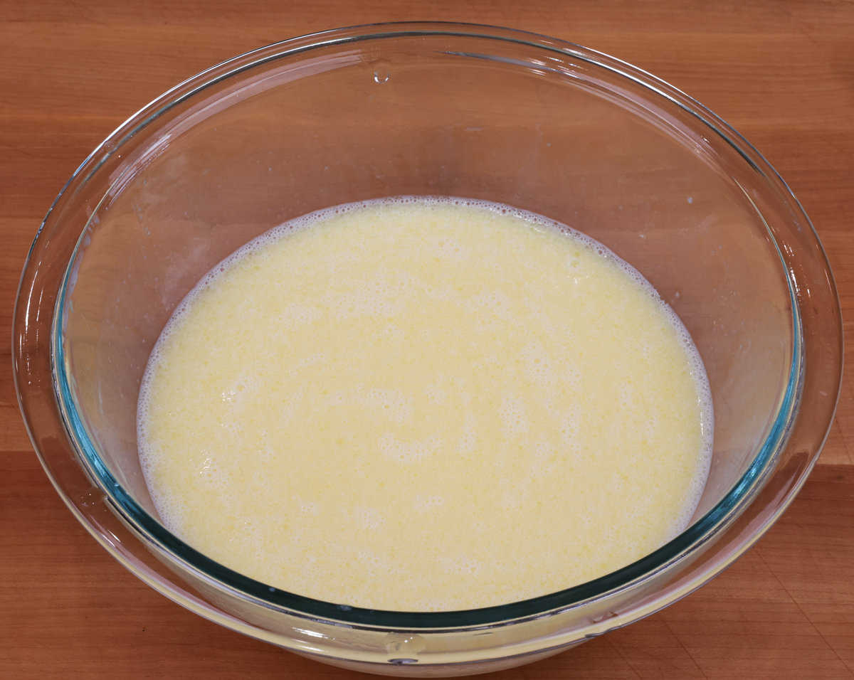 an egg, milk, vanilla, and melted butter in a mixing bowl.