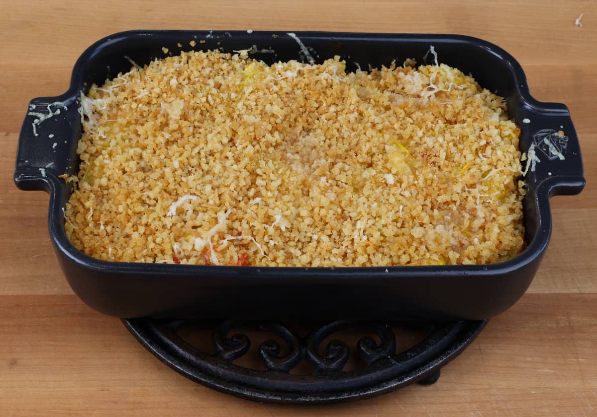 a small squash casserole topped with breadcrumbs cooling on a kitchen counter.