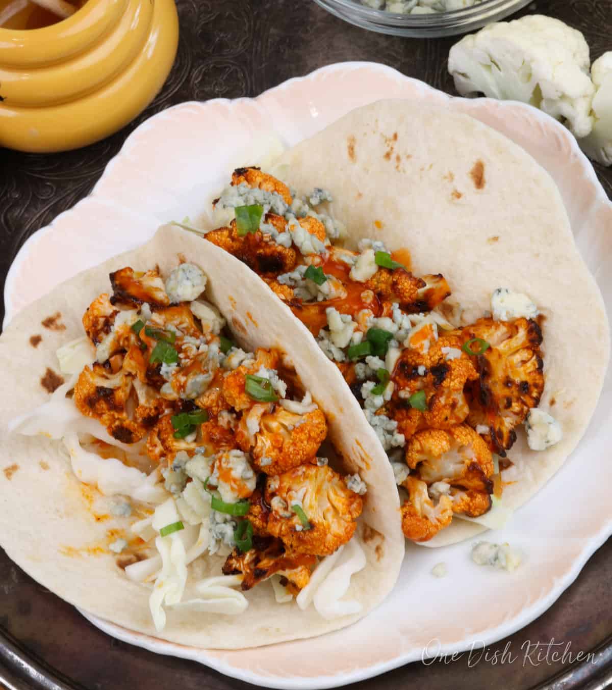 two tacos filled with buffalo cauliflower and shredded cabbage.