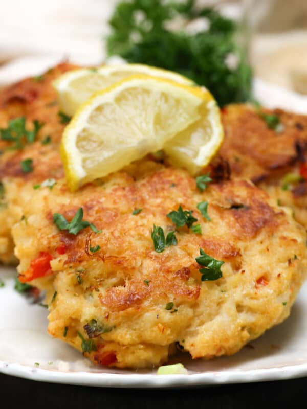 three crab cakes on a white plate topped with lemon slices