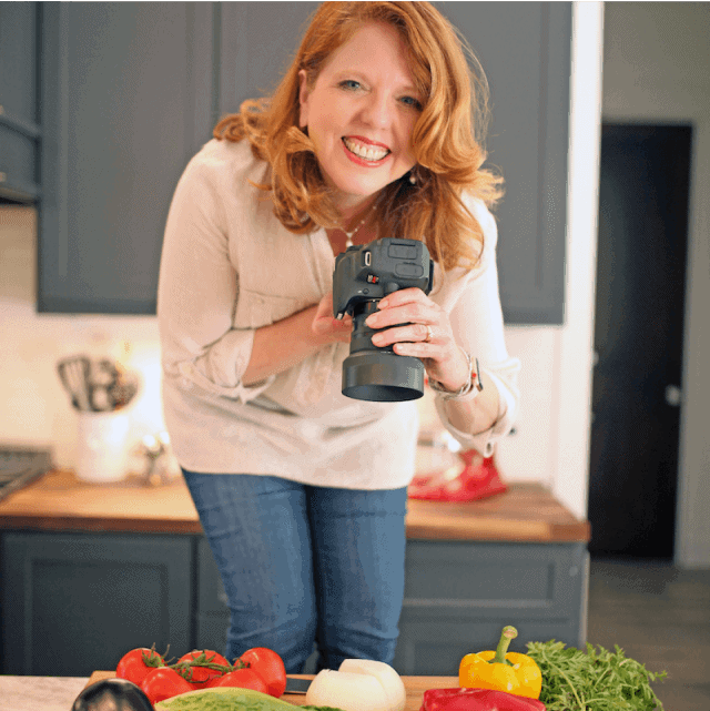 A women with red hair holding a camera.