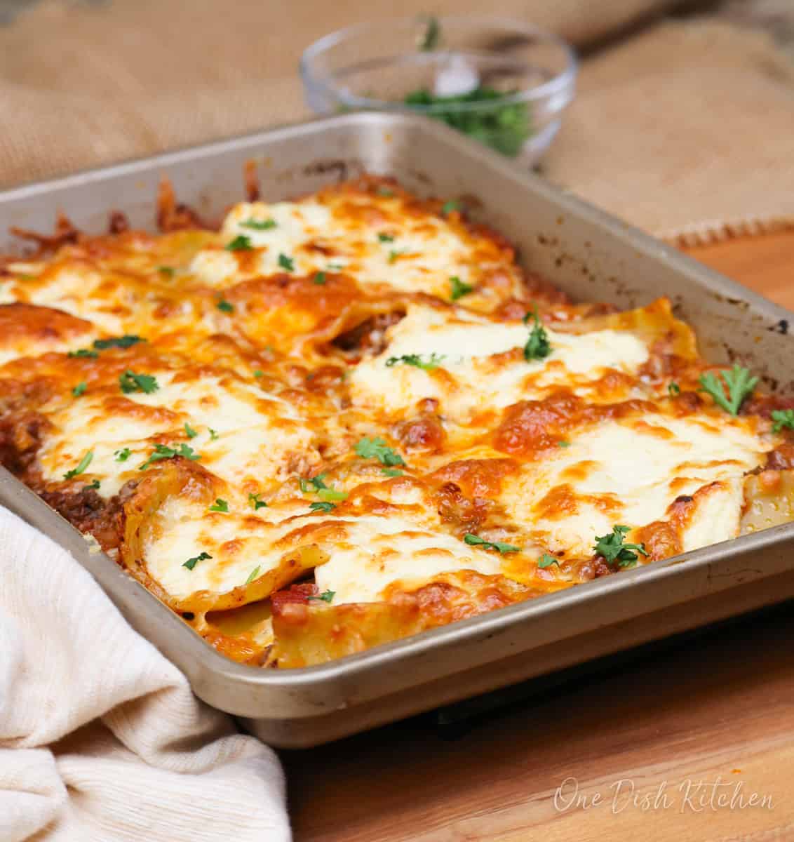 a small sheet pan lasagna next to a brown napkin.