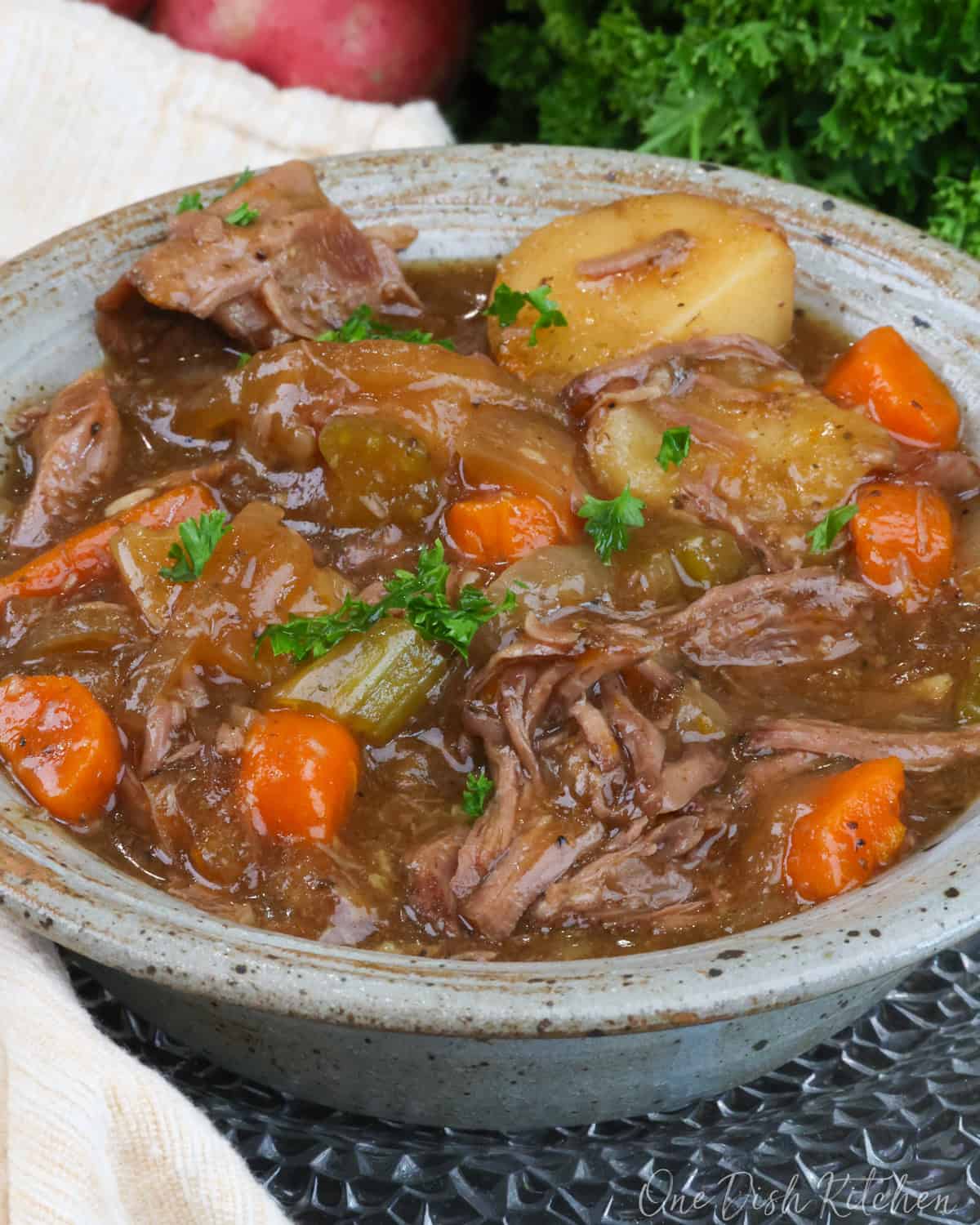 a blue bowl filled with a pot roast and vegetables.