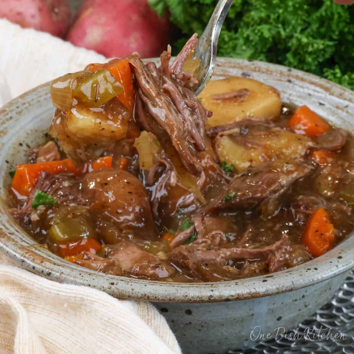 The finished mini slow cooker pot roast for one served with tender vegetables and rich gravy.